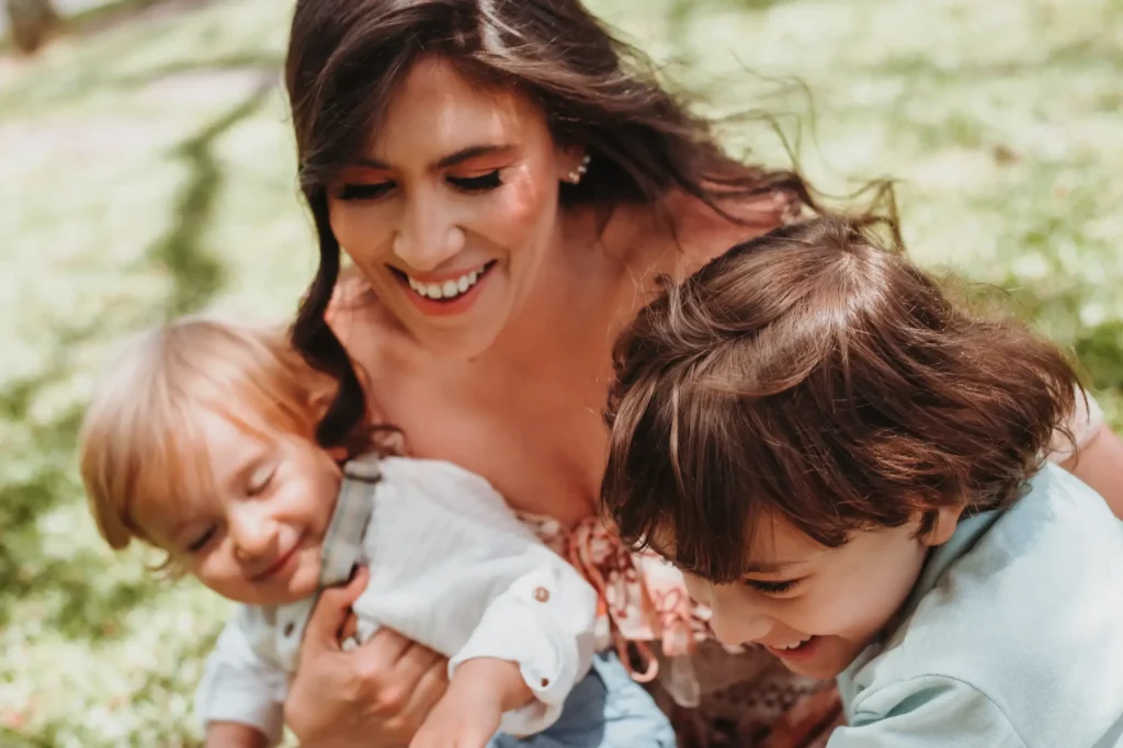 Smiling mother playing outside with two young children, symbolizing the importance of child support in maintaining a child’s well-being.