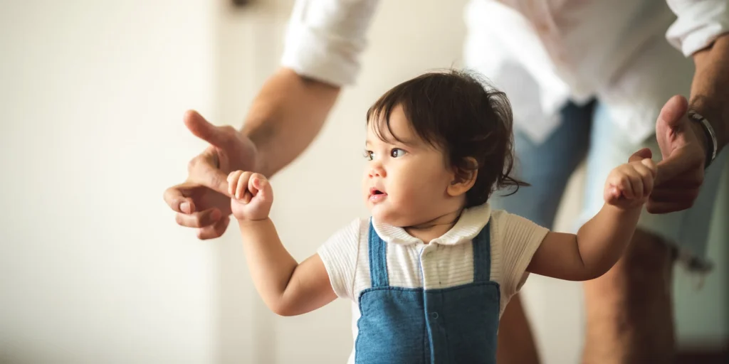 Baby holding father’s fingers while walking, symbolizing child care supported by Texas child support law.