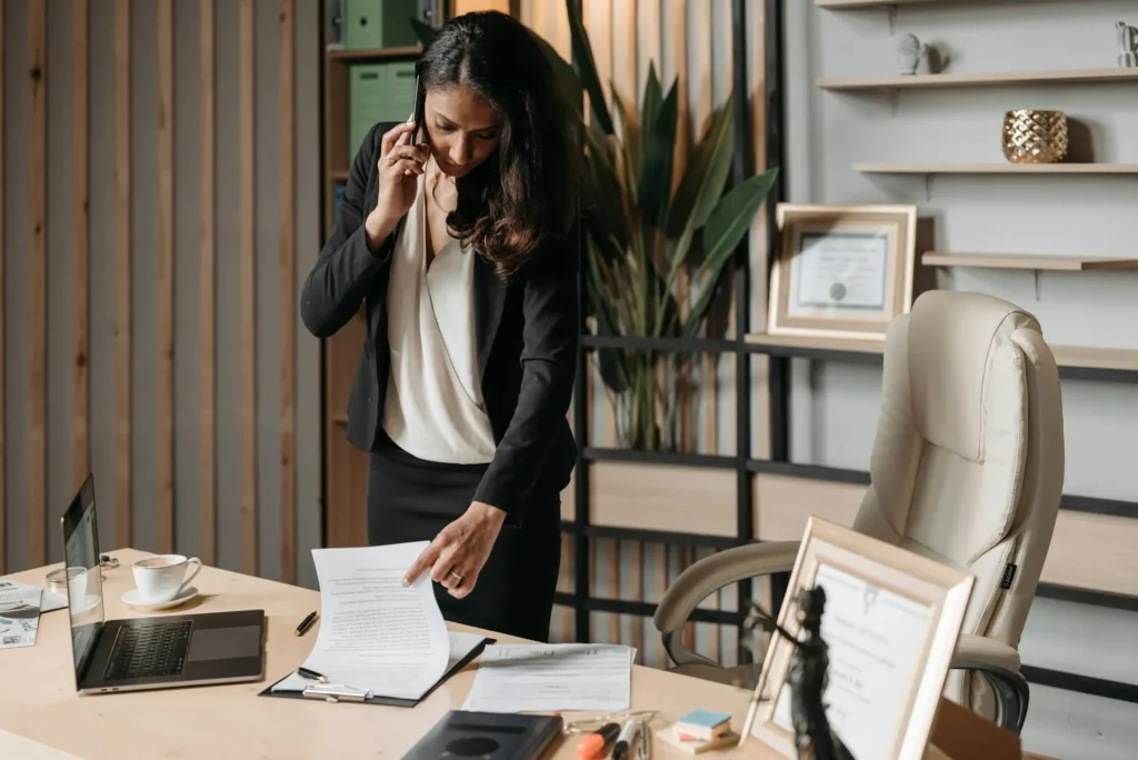Female professional in an office reviewing documents and speaking on the phone, symbolizing choosing a lawyer for divorce.